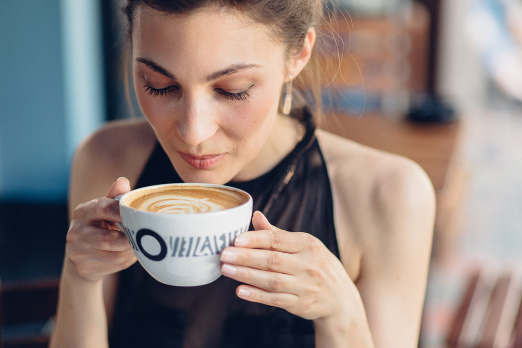 Девушка пьет кофе из чашки в кафе