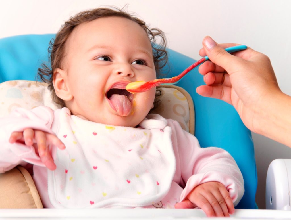 Ребенок открывает рот перед ложкой с пюре