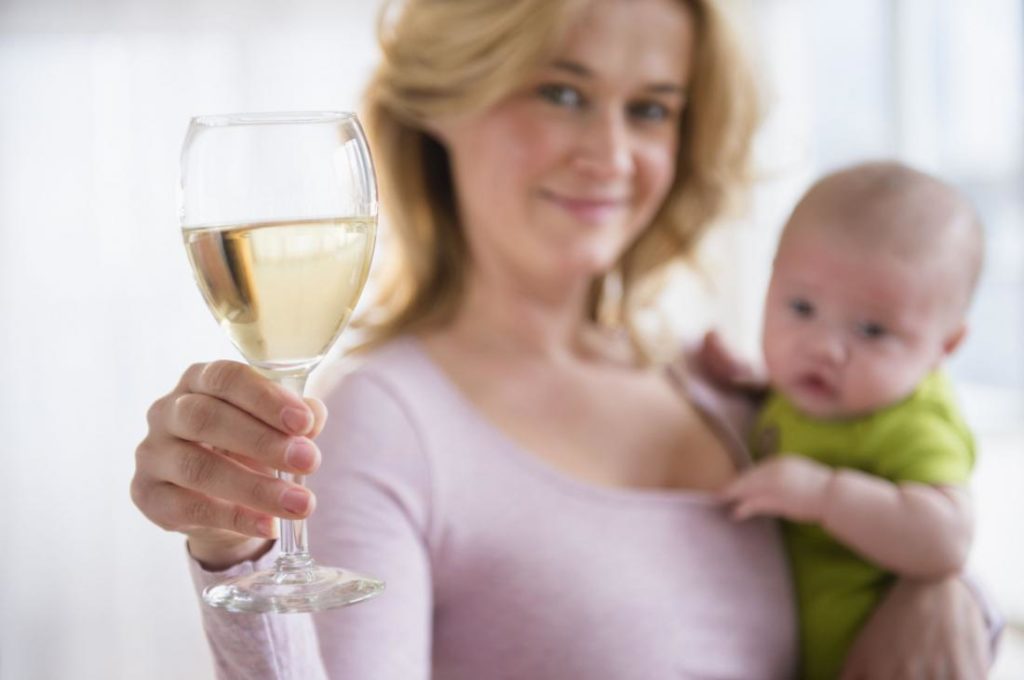Женина держит одной рукой ребенка, а другой бокал белого вина