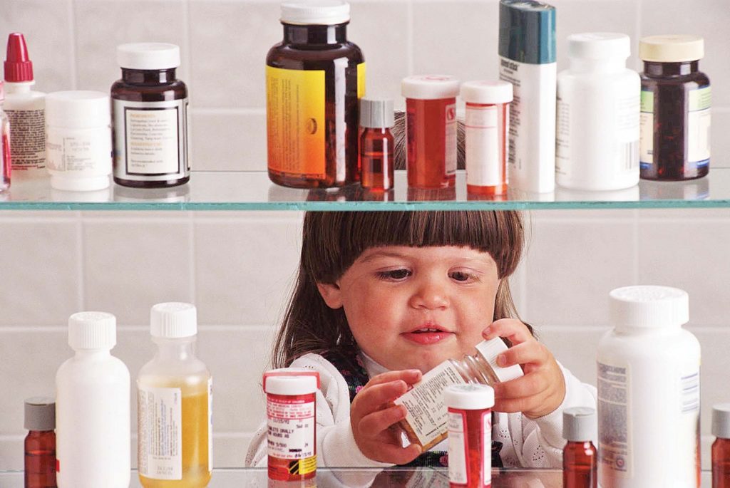 Ребенок берет банки с лекарствами с полки