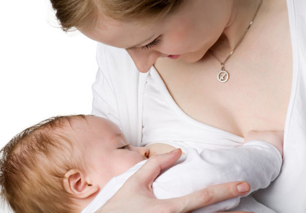 Женщина кормит грудью младенца