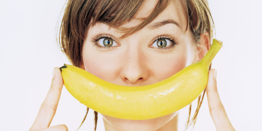 Девушка держит банан перед ртом
